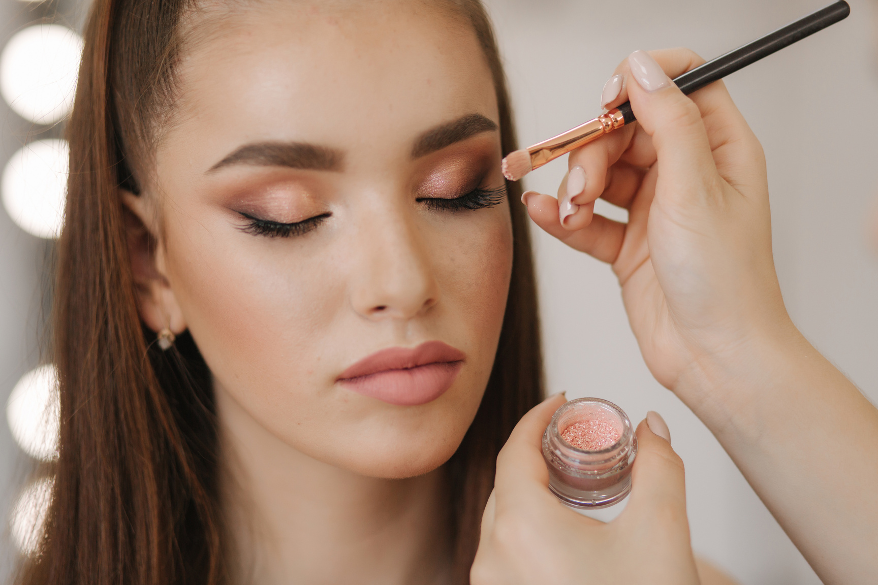 Makeup artist applies eye shadow, perfect evening makeup. Beauty redhead girl with perfect skin and freckles